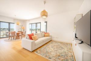 een woonkamer met een witte bank en een tv bij GuestReady - Tranquil Seixal Haven in Seixal