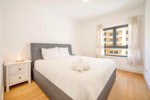 een slaapkamer met een groot wit bed en een raam bij GuestReady - Tranquil Seixal Haven in Seixal