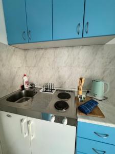 a kitchen with a stove and a sink and blue cabinets at Prijevor Apartments in Budva