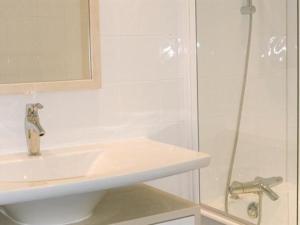 ein weißes Bad mit einem Waschbecken und einer Dusche in der Unterkunft Short Stay Paris Apartments in Paris