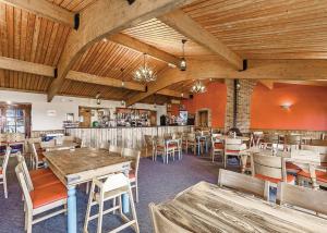 een restaurant met houten plafonds en tafels en stoelen bij Bucklegrove Holiday Park in Rodney Stoke