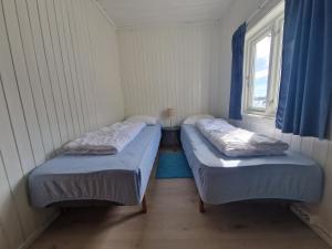 two beds in a small room with a window at Sjøstrand Rorbuer v Børge Iversen AS in Ballstad