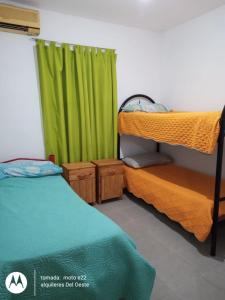 1 dormitorio con 2 literas y cortina verde en Alquileres del oeste en La Rioja