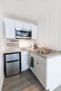 a white kitchen with a sink and a microwave at Anchor Bay Inn and Suites in Sandusky