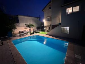 a swimming pool in front of a house at night at Charmante maison au Nord de Paris piscine chauffée in Argenteuil +8 photos