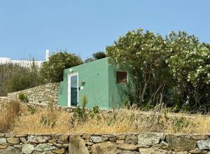 una casa verde en la parte superior de una pared de piedra en Mykonos Love Nest, en Ano Mera