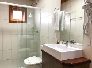 uma casa de banho com um lavatório, um chuveiro e um WC. em Hotel Triveneto Gramado em Gramado