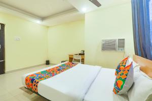 a bedroom with a white bed with a colorful blanket at FabHotel Magadh Regency in Patna