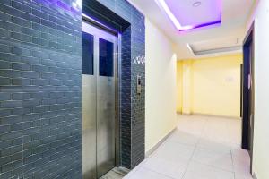 a hallway with a walk in shower with blue tiles at FabHotel Magadh Regency in Patna