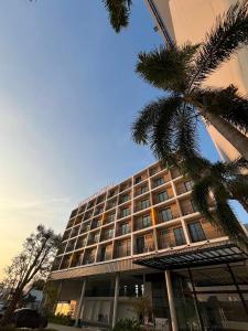a building with a palm tree in front of it at Hatyai Midtown Hotel in Hat Yai