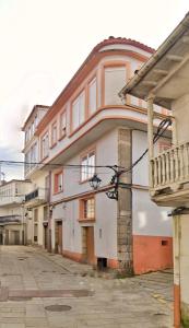 um edifício branco com uma varanda numa rua em Apartamento en el casco historico de Betanzos em Betanzos