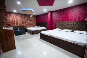um quarto com 2 camas e uma parede vermelha em Parinay Vatika Inn em Deoghar