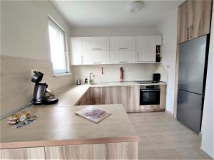a kitchen with white cabinets and a stainless steel refrigerator at Rozina by RV Apartments in Kazanlŭk