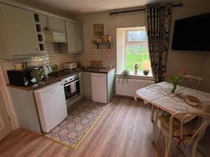 a kitchen with a table and a table and a window at Riverside Cottage in Tassagh