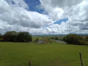 a green field with a fence and a cloudy sky at Soleil levant au domaine de Tara in LʼHôpital-du-Grosbois