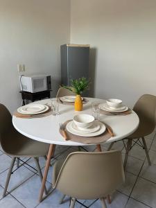 a white table with chairs and plates and a microwave at Residencial Castelinho in Mucuri