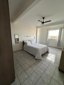 a white bedroom with a bed and a ceiling fan at Residencial Castelinho in Mucuri