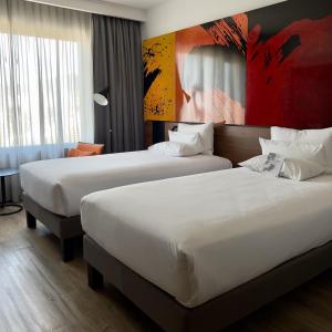 a hotel room with two beds and a painting on the wall at Novotel Santiago Providencia in Santiago