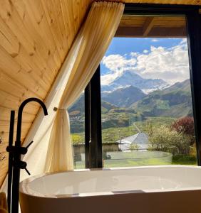 baño con bañera y ventana con vistas a las montañas en Kuro cottage- A frame en Kazbegi
