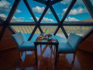 two chairs and a table in front of a large window at Domos Zen San Luis in Estancia Grande +26 photos