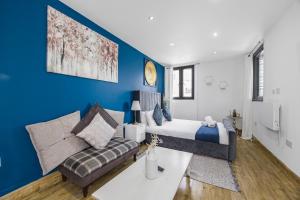 a bedroom with blue walls and a bed and a couch at Marylebone City Apartments in London