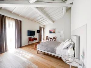 a white bedroom with a bed and a desk at Suite Greve in Chianti in Greve in Chianti