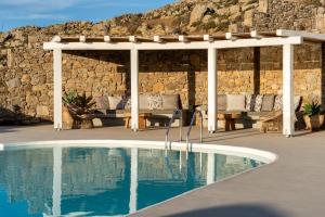 una pérgola y una piscina junto a una pared de piedra en Velanos Villa en Plintri