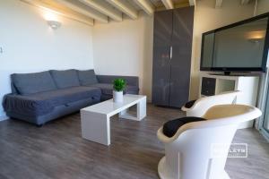 a living room with a couch and a flat screen tv at Vias-Plage - Appartement climatisé avec piscine face à la mer in Vias