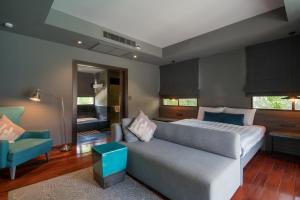 una camera da letto con un letto, un divano e una sedia di Anchan Boutique Resort and Spa a Ban Thalat Choeng Thale