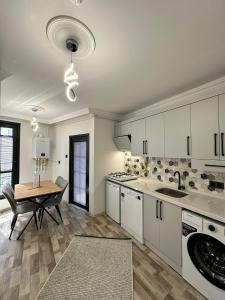 a kitchen with white cabinets and a table and a dining room at Öztürk VIP in Pelitli