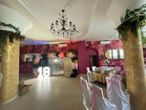un salón de banquetes con paredes rosas y una lámpara de araña en Pensiunea Ileana, en Sibiu