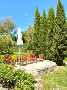 una mesa y dos bancos y una sombrilla en un parque en Relais Poggio Del Melograno en Montecatini Val di Cecina