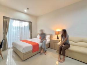 Dos personas sentadas en una cama en una habitación de hotel en Uou Hotel en Kabin Buri