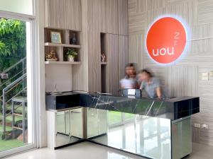 two people standing at a counter in a lobby at Uou Hotel in Kabin Buri