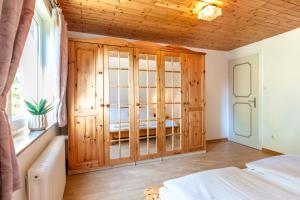 1 dormitorio con armarios de madera, 1 cama y ventana en alkoven, en Oldsum
