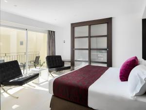 a bedroom with a bed and two chairs and a balcony at Hotel Saratoga in Palma de Mallorca