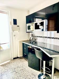 a black and white kitchen with a counter and a microwave at Le mont canigou in Taurinya
