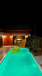 a swimming pool at night with a raft in it at MARENA Poolvilla UdonThani in Udon Thani