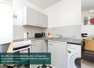 uma cozinha com armários brancos e uma máquina de lavar e secar roupa em Clarence Suite - Free Parking em Chatham