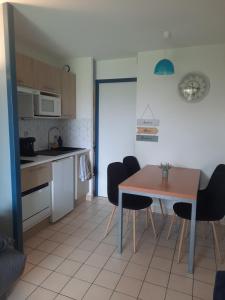 eine Küche und ein Esszimmer mit Tisch und Stühlen in der Unterkunft Studio 4 pers / terrasse / espace aquatique in Talmont