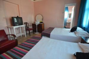 a hotel room with two beds and a tv at Holiday Home - Guest House in Port Antonio