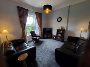 a living room with two leather couches and a television at McCaig's View in Oban