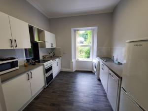 a large kitchen with white appliances and a window at McCaig's View in Oban