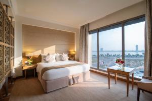 Habitación de hotel con cama y ventana grande en Golden Tulip Dammam Corniche Hotel en Dammam