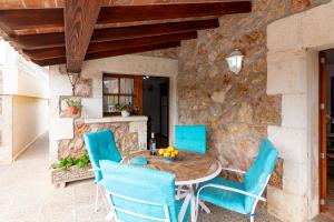 ポリェンサにあるVilla Colonya Jaume-3 bedrooms, private pool near Pollensaの石壁のパティオ(テーブル、青い椅子付)