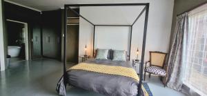 1 dormitorio con cama con dosel y silla en Rand Self-catering Accommodation, en Carolina