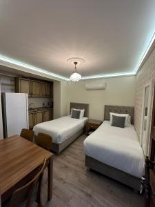 イスタンブールにあるカテルヤ ホテルのベッド2台、テーブル、冷蔵庫が備わる客室です。
