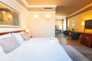 a bedroom with a white bed and a living room at BRISTOL Hotel Opatija in Opatija