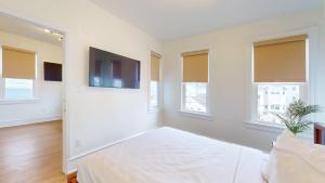 a white bedroom with a bed and a flat screen tv at The Cove in Ocean City