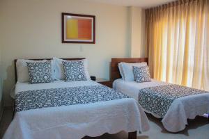 a hotel room with two beds and a window at San Juan Del Lago in Pereira